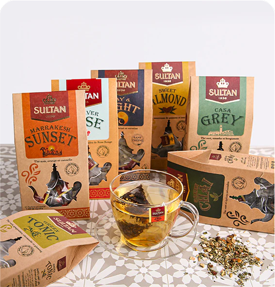 Assortment of Sultan Tea packets and boxes with a glass cup of tea on a patterned table